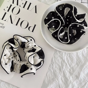 Detail view of black and white polka dot chiffon scrunchies on a white ceramic plate