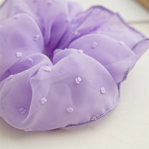 Detaillierte Makroansicht des lila Netzstoffs und der weißen Flockpunkte auf dem Scrunchie