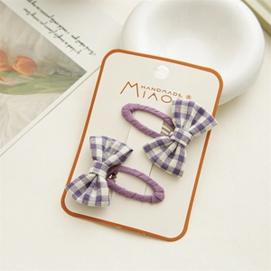 Detailed view of purple checkered bow hair clips on a cream display card for girls