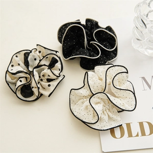 Detailed view of three polka dot scrunchies with contrasting edges and ruffled fabric texture