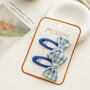 Close-up of blue plaid bow hair clips on handmade card with aesthetic background