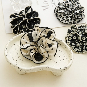 Close-up of elegant floral and polka dot fabric scrunchies with refined black edge piping