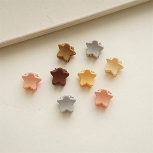 Detail of star-shaped mini hair clips in matte Morandi colors on a warm white background