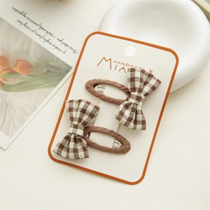 Detail of two handmade brown plaid fabric bow hair clips on branded packaging card