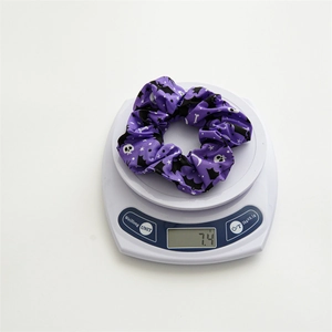 Chouchou violet d'Halloween en satin avec motifs de crânes pesant 7,4g sur balance