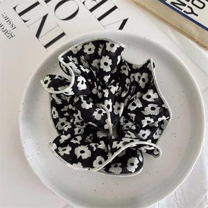 Detail of floral scrunchie with white scalloped edging on a stylish ceramic plate