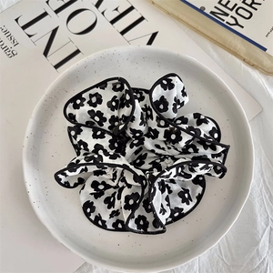 Detail of floral chiffon scrunchie with black piping edges and elegant ruffles