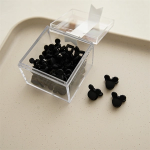 Macro shot of mini black matte Mickey-shaped hair clips in a clear acrylic storage box