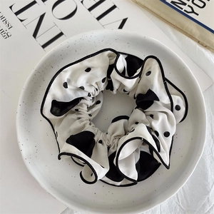Close-up detail of oversized black and white polka dot chiffon scrunchie with hemmed edges