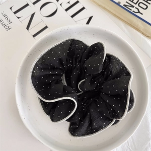 Detail of black polka dot chiffon scrunchie with white edge piping on ceramic plate