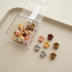 Detailed view of star-shaped mini hair clips in morandi colors on a beige tray