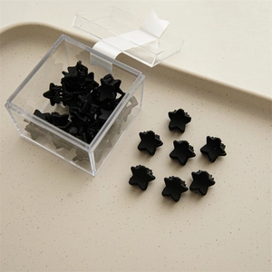 Close-up of black star-shaped mini hair claws in a clear acrylic box and a matte tray