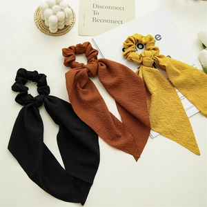 Detail of plaid scrunchies with long ribbons in black, orange, and yellow autumn tones