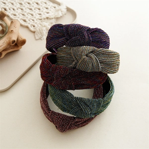 Set of four shimmering knotted fabric headbands in assorted metallic colors on beige background
