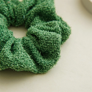 Gros plan d'un chouchou en tweed vert avec texture pailletée et tissu épais