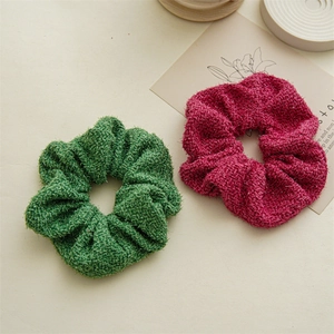 Détail de chouchous en tweed vert et rose magenta avec une texture de fibre scintillante