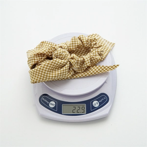 Polyester plaid scrunchie with streamer on weighing scale showing weight of 22.9g