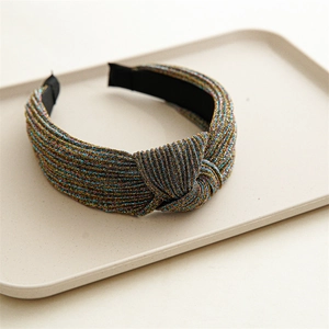 Detail view of a knotted wide headband featuring colorful metallic lurex weave texture