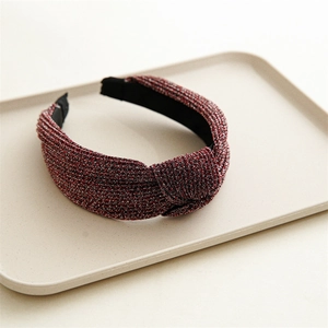 Detail of red metallic woven fabric headband with a stylish top knot on a tray
