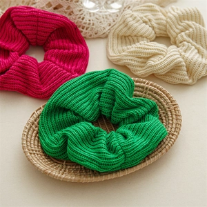 Macro view of textured knitted scrunchies in bright green, pink, and beige yarn