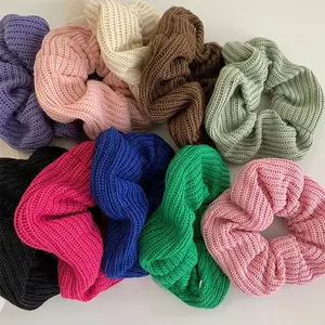 Detail showing oversized knitted hair scrunchies in various solid colors and thick textures