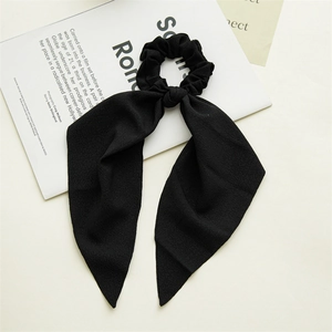 Detail of elegant black chiffon scrunchie with long ribbon streamers on a magazine