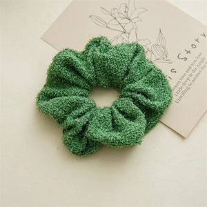 Détail de la texture du chouchou en tweed vert avec fils argentés pour chignons