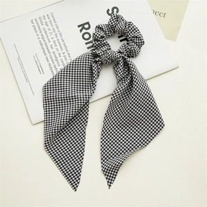 Detail of black and white gingham scrunchie with long ribbon on a magazine