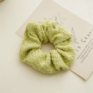 Gros plan d'un chouchou en tweed vert clair avec texture tissée sur carte