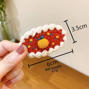Vue détaillée de la barrette en laine faite main, accessoire de 6cm x 3,5cm en fil rouge et blanc