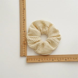 Chunky cream knitted scrunchie hair tie with ribbed wool texture and measuring ruler