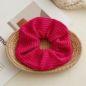 Detail of soft chunky rose pink knitted scrunchie with rib texture on wooden tray