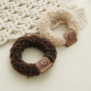 Chouchous en peluche à sourire en marron et beige avec une texture douce et bouclée