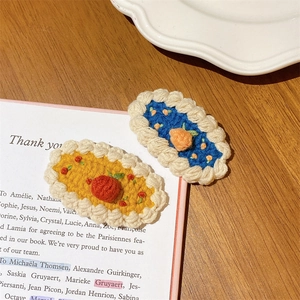 Détail de pinces à cheveux fraises au crochet faites main sur un livre vintage pour filles