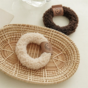 Détails des chouchous en peluche beige et marron avec étiquette sourire dans un panier