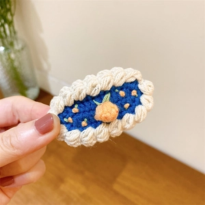 Gros plan sur une pince à cheveux au crochet avec base bleue et fleurs orange