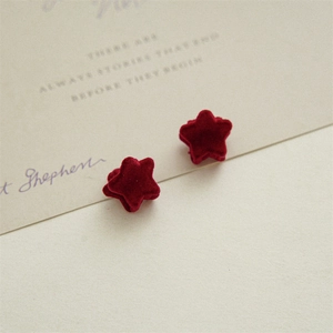 Macro detail of red velvet star-shaped hair clips showing soft texture on card base