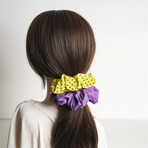 Polka dot and solid purple hair scrunchies set on a low ponytail with chic style