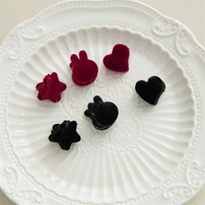 Detailed view of mini velvet heart and star hair clips in a white vintage ceramic dish