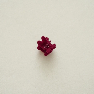 Macro view of a mini wine red velvet hair claw clip with a plush texture and small spring