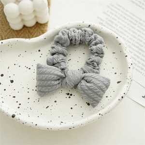 Macro shot of grey cable knit bow hair scrunchie on a decorative ceramic tray