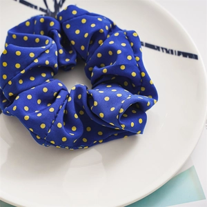 Close-up of a blue and yellow polka dot scrunchie on a white ceramic plate