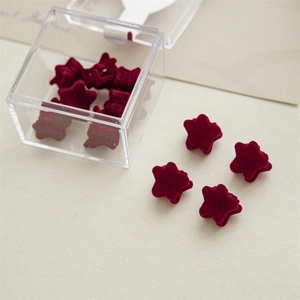 Detailed view of burgundy velvet star hair clips stored in a clear plastic organizer box