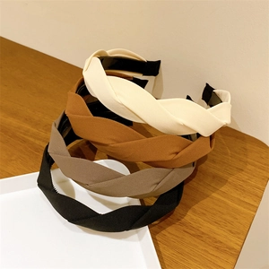 Detailed view of four twisted wide headbands in cream, caramel, taupe, and black colors