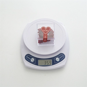 Mini red velvet star hair clips in a clear branded box shown on a scale for weight