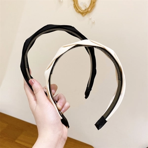 Detail of twisted fabric headbands with non-slip inner teeth in black and beige cream