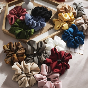 Close-up of assorted satin silk scrunchies in vibrant colors on a wooden tray