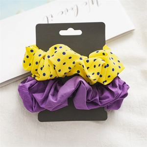 Close-up of yellow polka dot and purple fabric scrunchies set on display card