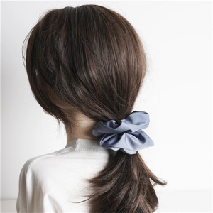 Detail of blue-grey satin scrunchie showing smooth fabric texture on a ponytail