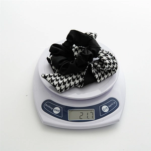 Detail shot of a houndstooth bow scrunchie on a scale showing its weight of 21.7g